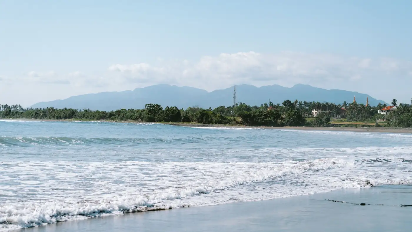 Illustrative photo of a calm beach with hills behind it