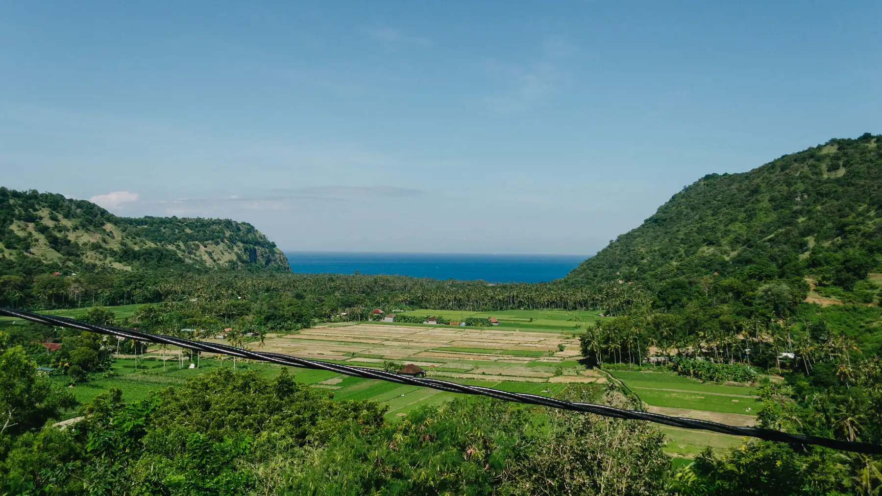 Illustrative photo of rice fields between hills with the sea beyond