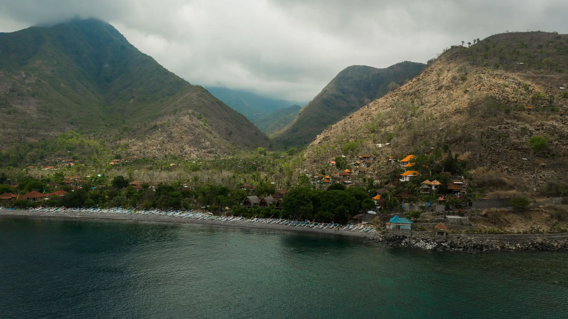 Illustrative aerial photo of a coastal village between green hills and a calm sea